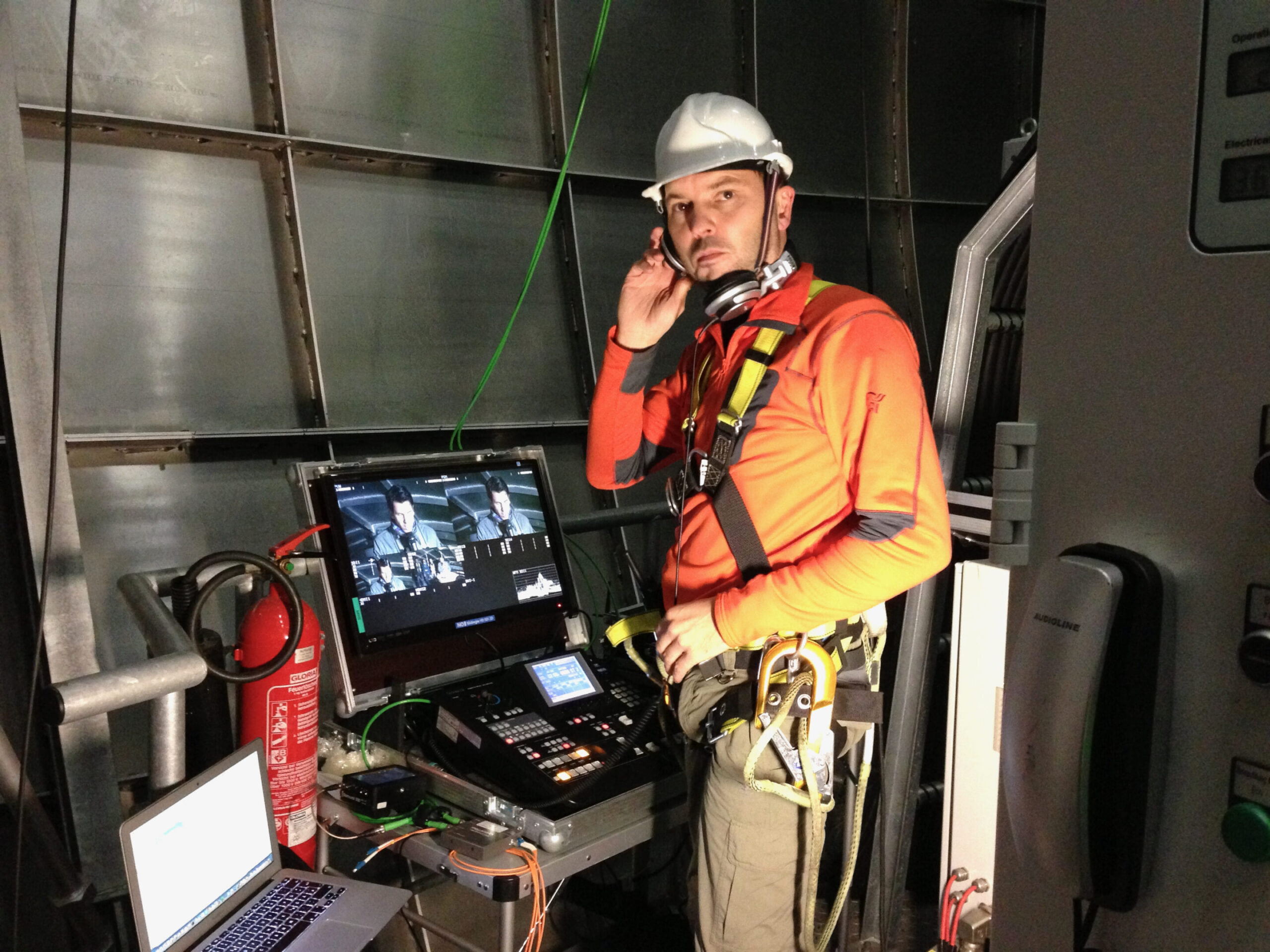Livestream-Techniker in Schutzausrüstung bedient Regie-Equipment in Industrieanlage